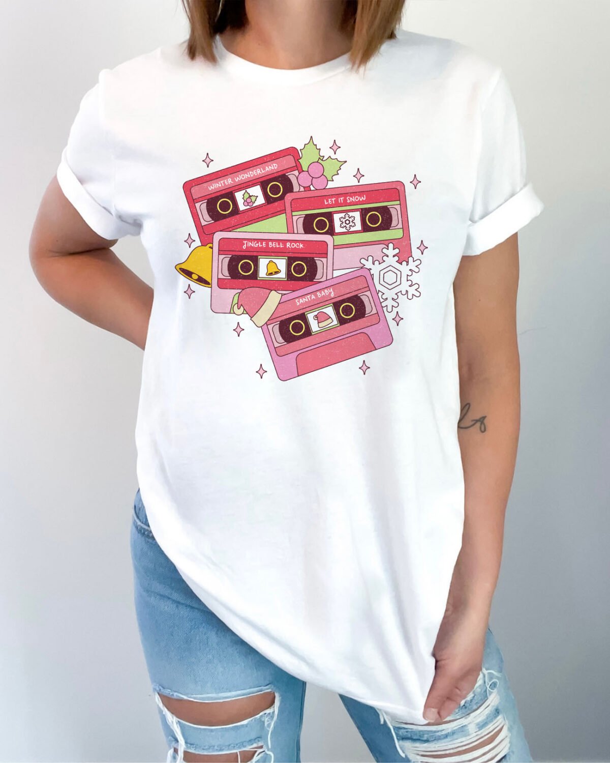 Woman wearing a Cassette Tapes Shirt in white color, featuring a retro cassette tapes graphic with in XMAS style.