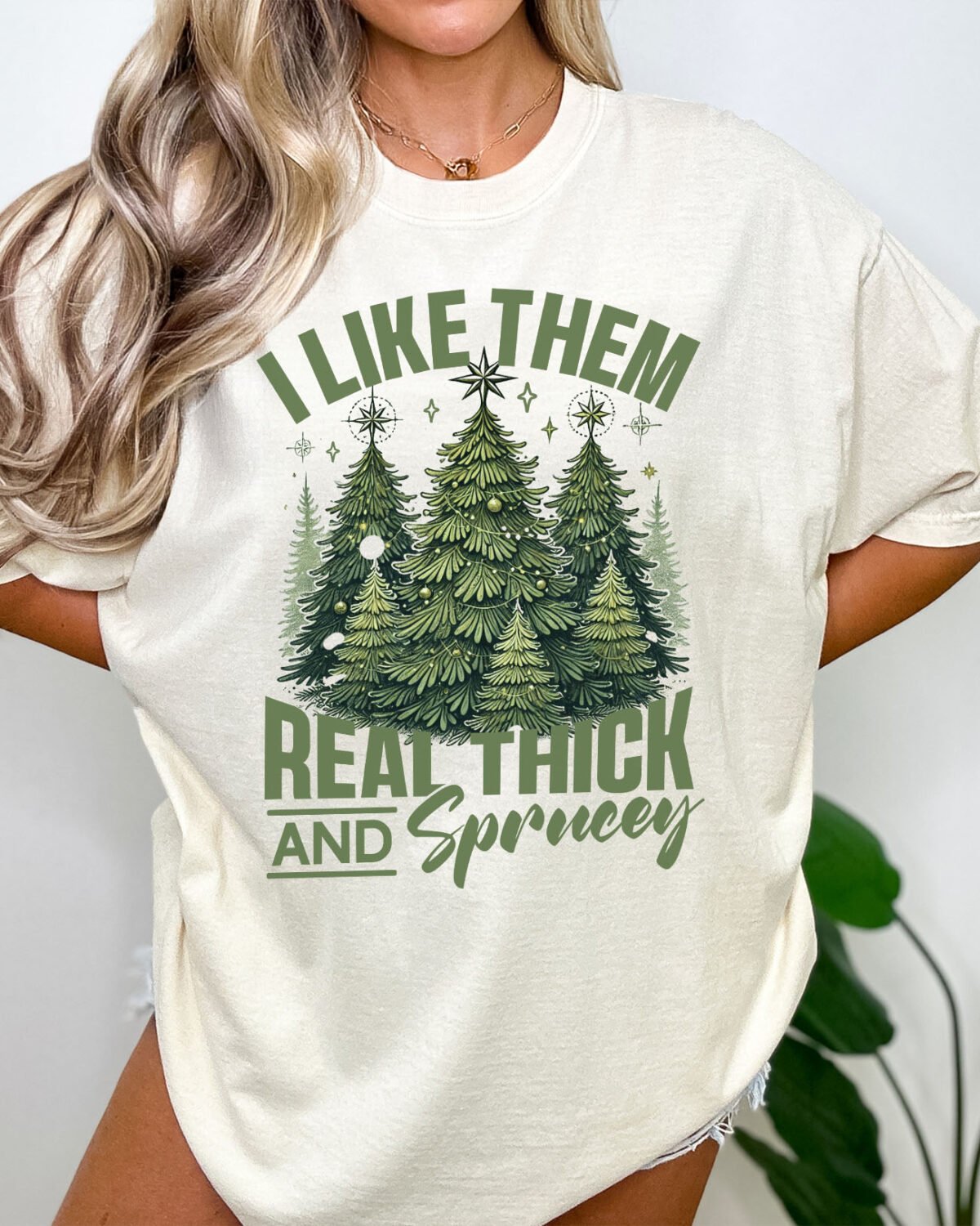 Woman wearing an "I like them real thick and sprucey" shirt in natural color featuring a funny christmas graphic