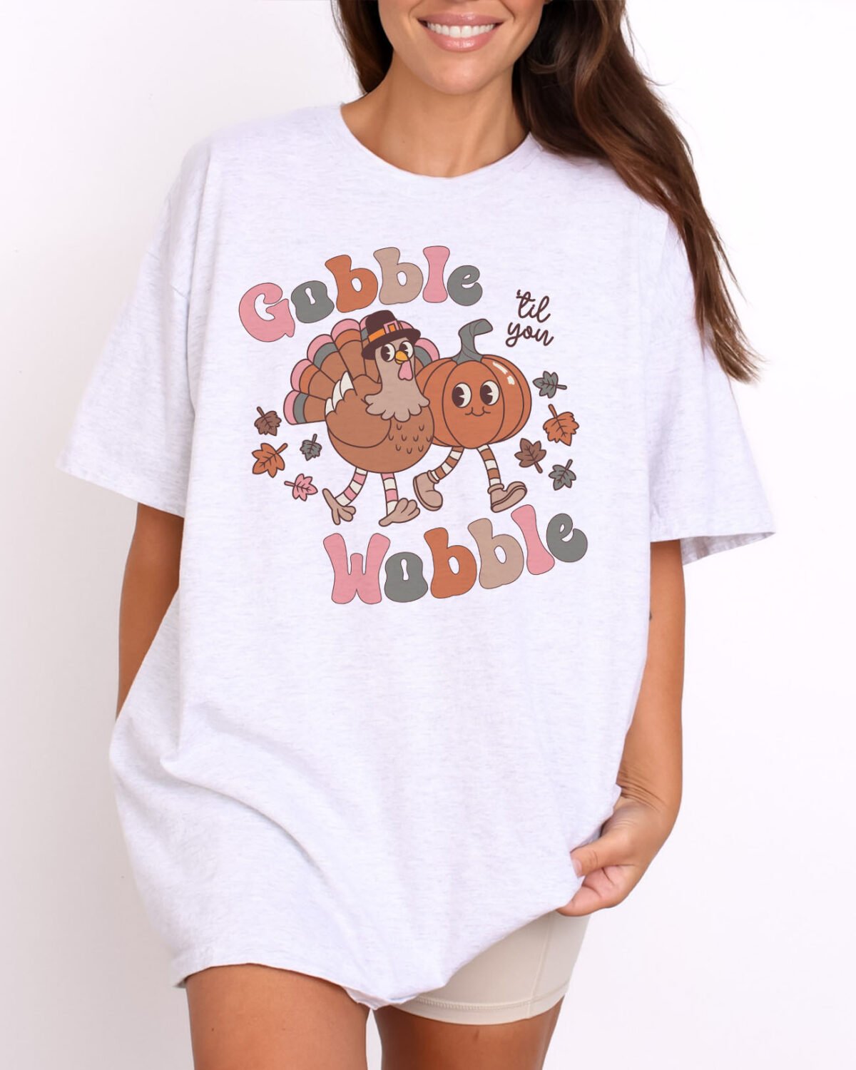 Woman wearing a funny Thanksgiving Gobble Til You Wobble shirt in ash color